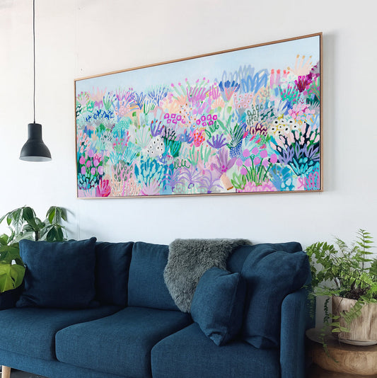 Blue sofa in a living room with a colorful abstract painting on the wall.