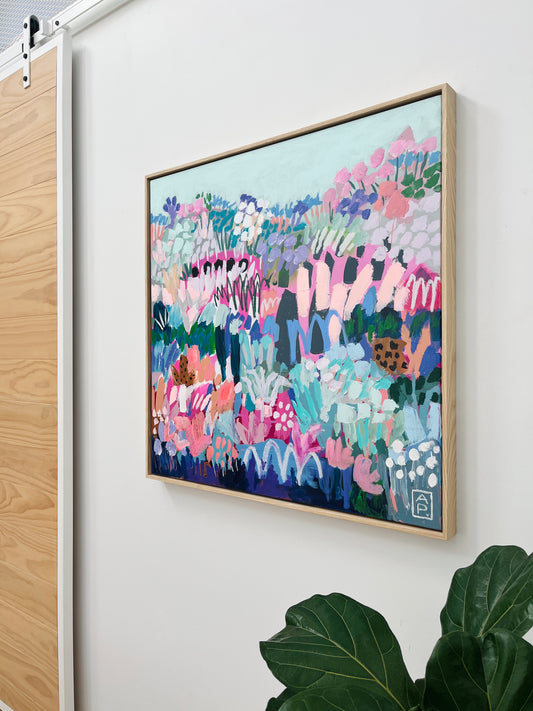 Colorful abstract painting on a white wall with a plant in the foreground