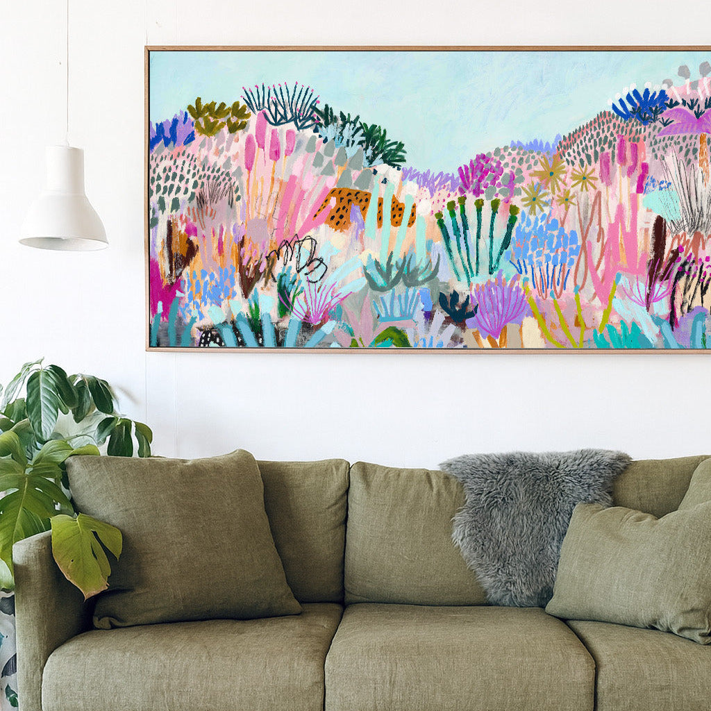 Green sofa with a colorful abstract painting above it in a room with plants.