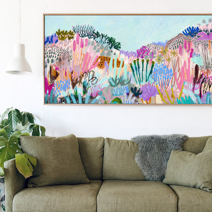 Green sofa with a colorful abstract painting above it in a room with plants.