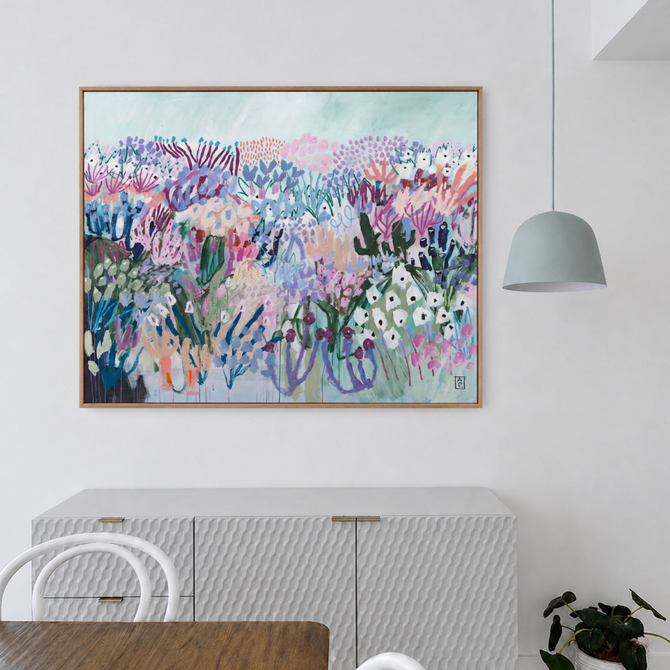 Colorful floral painting on a wall above a white cabinet in a modern room.