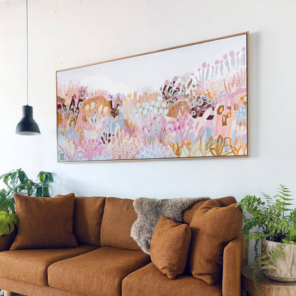 Brown sofa in a living room with a colorful abstract painting above it.