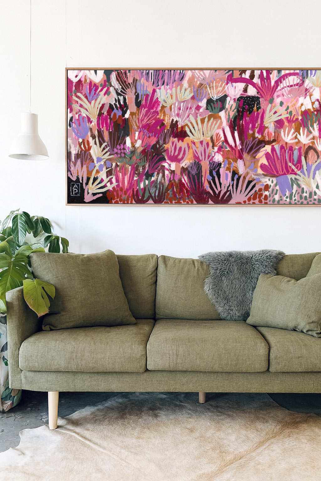 Green sofa with decorative pillows in a room with a colorful abstract painting on the wall.