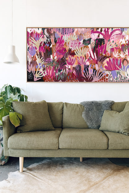 Green sofa with decorative pillows in a room with a colorful abstract painting on the wall.