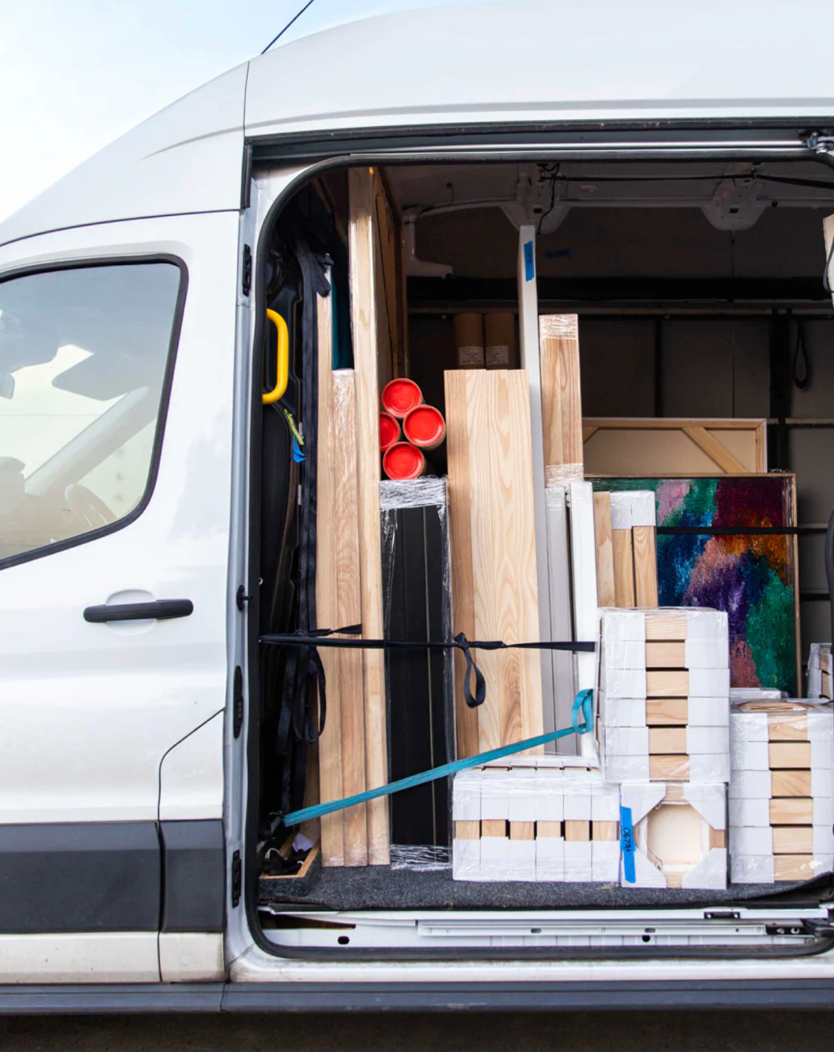 Van with open door showing various items including wood planks and a ladder.