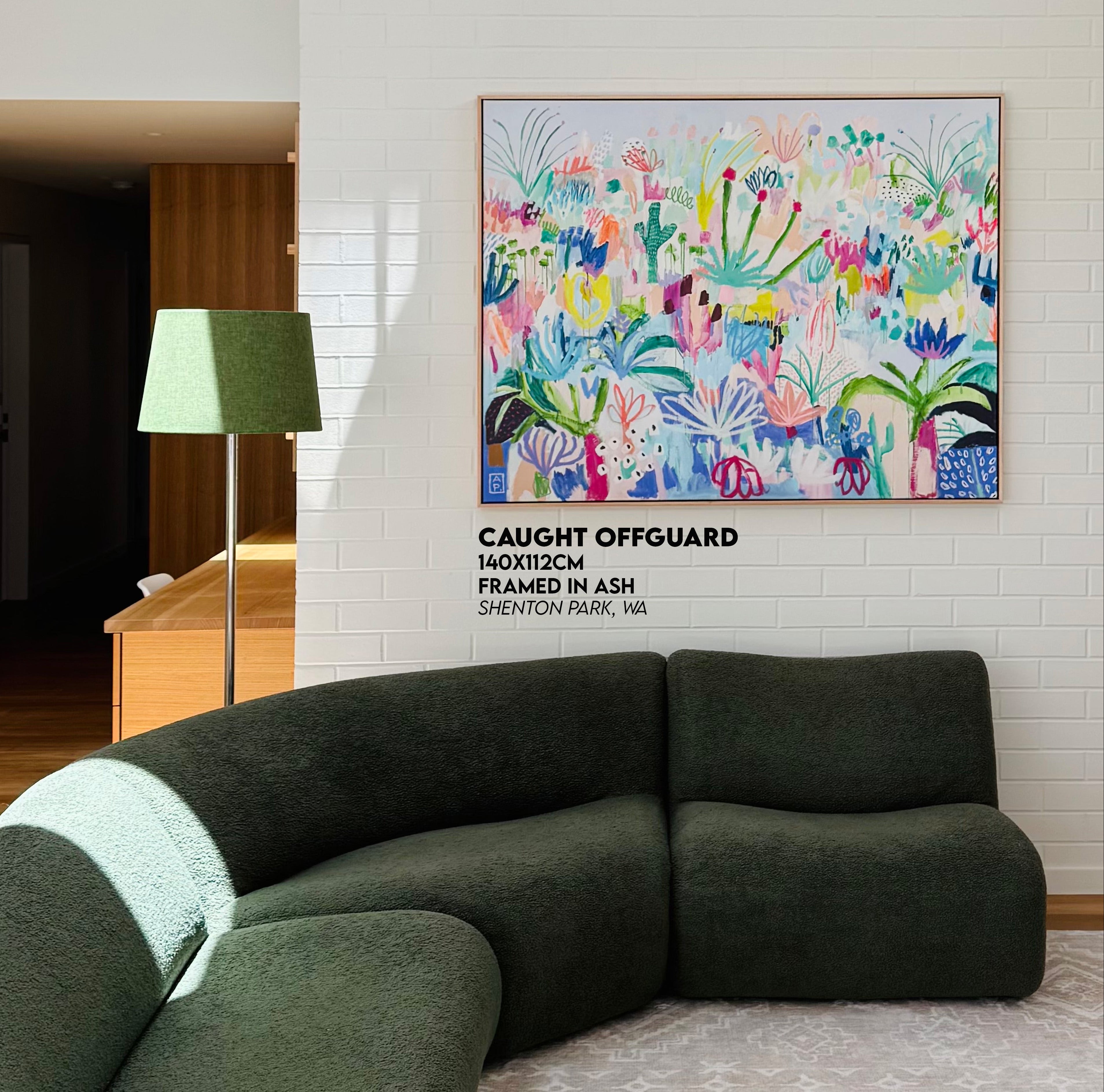 Modern living room with a green sofa and colorful abstract painting on the wall.