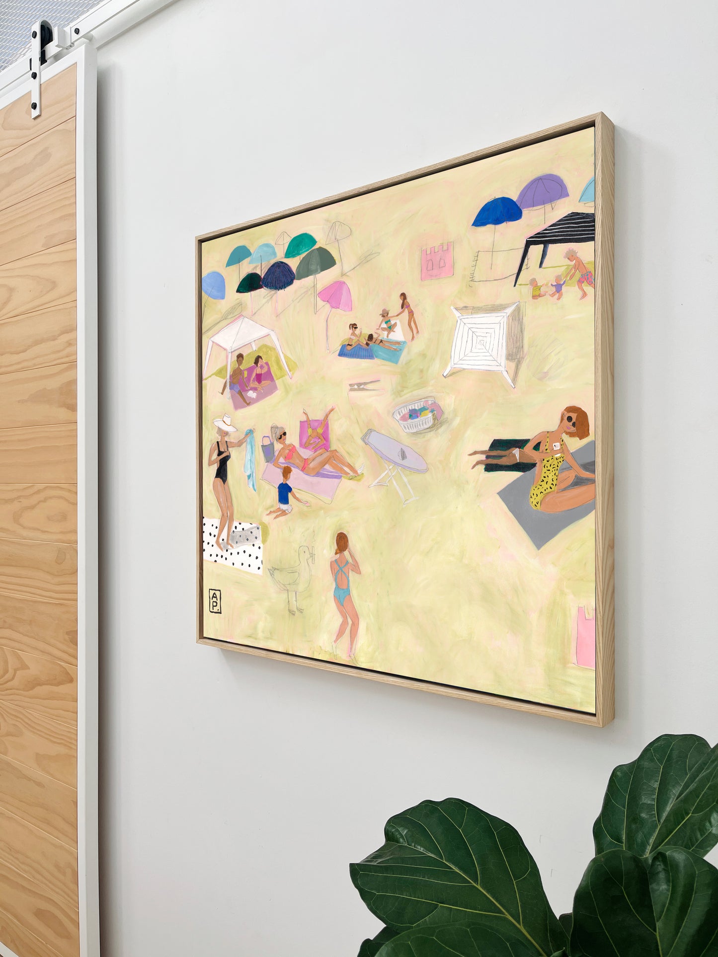 Framed artwork with a colorful beach scene on a white wall.